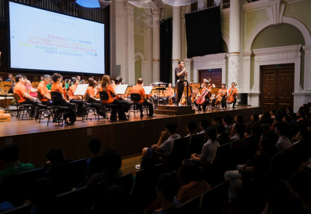 Conductor Jason Lai unpacking music with a hall filled with students at the Performing Arts-Based Learning (PABL) Concert