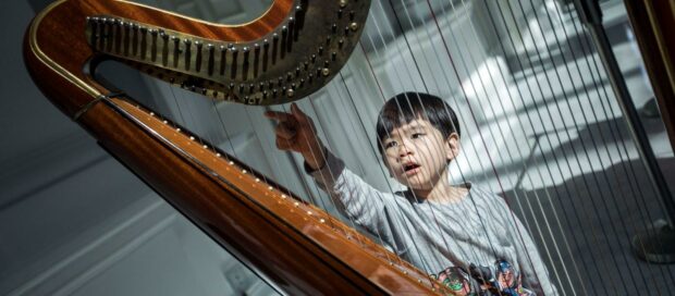 Young concertgoer interacts with a harp during Babies Proms pre-concert fun. (Photo Credit: Chrisppics+)